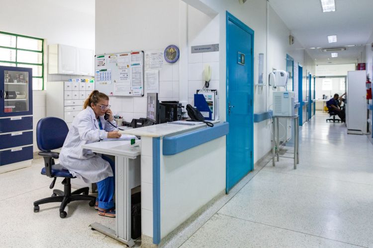 Corredor de hospital com atendente de saúde ao telefone
