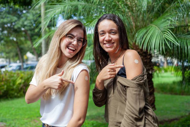 Meninas apontam para braço após vacinação