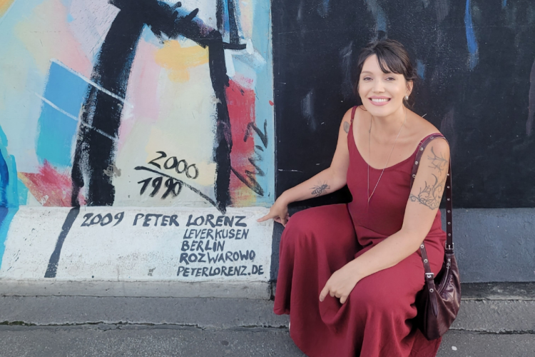 Camila ao lado de pintura do artista alemão Peter Lorenz na parte oriental do Muro de Berlim