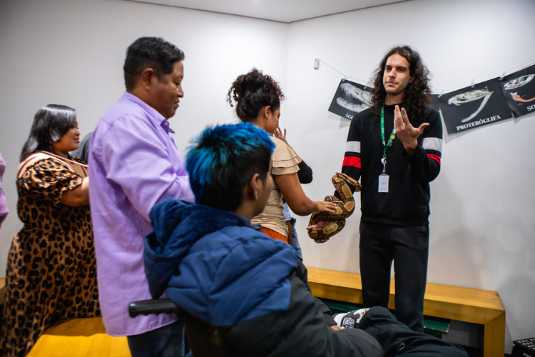 O líder educacional Lua Bissoli Silva apresenta a jiboia Afonso para os visitantes