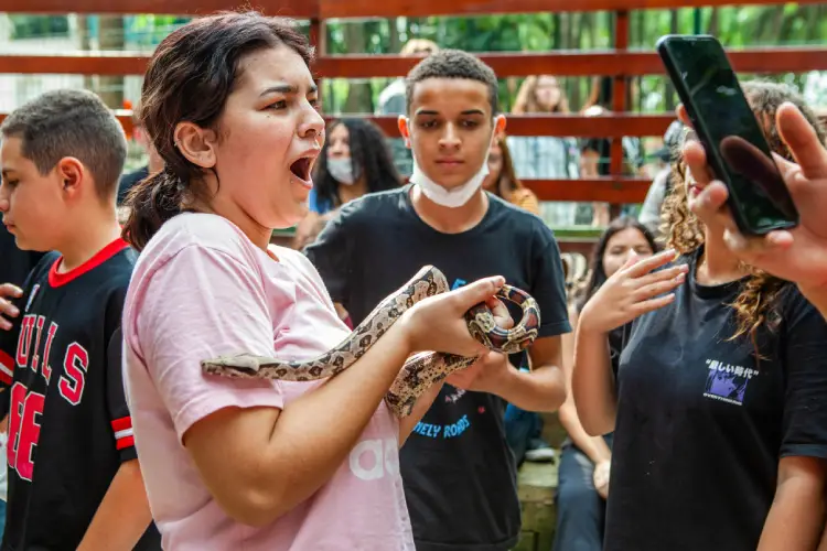 Visitante segura uma serpente durante atividade "Mão na Cobra"
