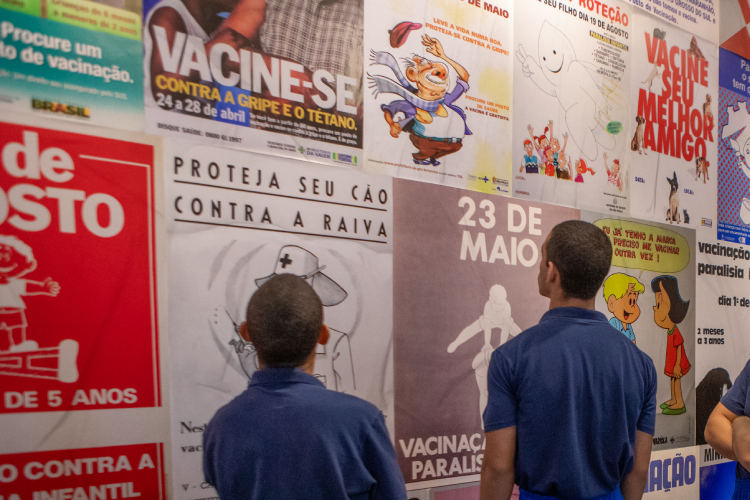 Meninos observam cartazes de campanhas de vacinação e tiram dúvidas sobre o assunto durante visita ao Museu da Vacina
