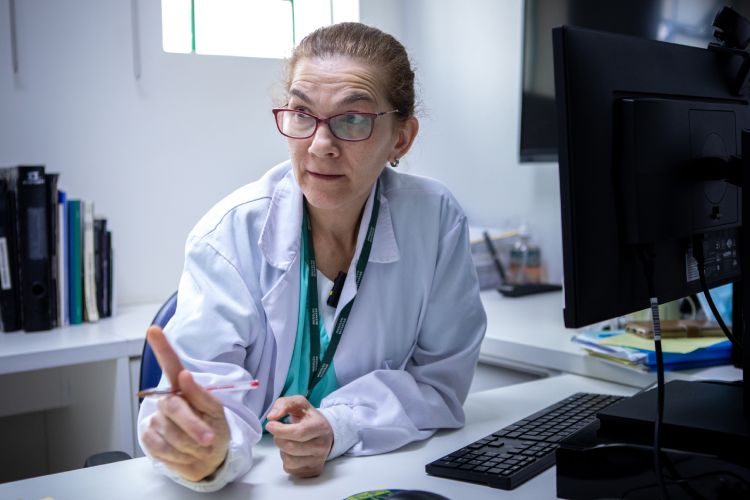 Mulher de óculos e jaleco de médico em ambiente hospitalar