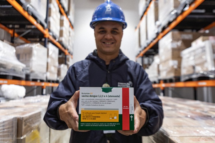 Colaborador com embalagem da vacina contra a dengue do Butantan