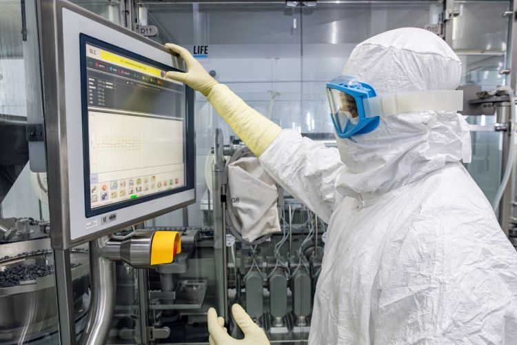 Imagem de colaborador paramentando operando máquina em fábrica de vacina