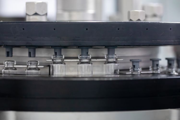 Frascos recebendo tampa de borracha em ambiente de fábrica