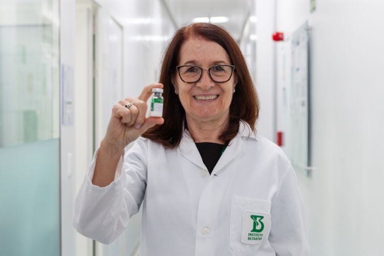 Pesquisadora segura ampola da vacina da dengue em ambiente de laboratório